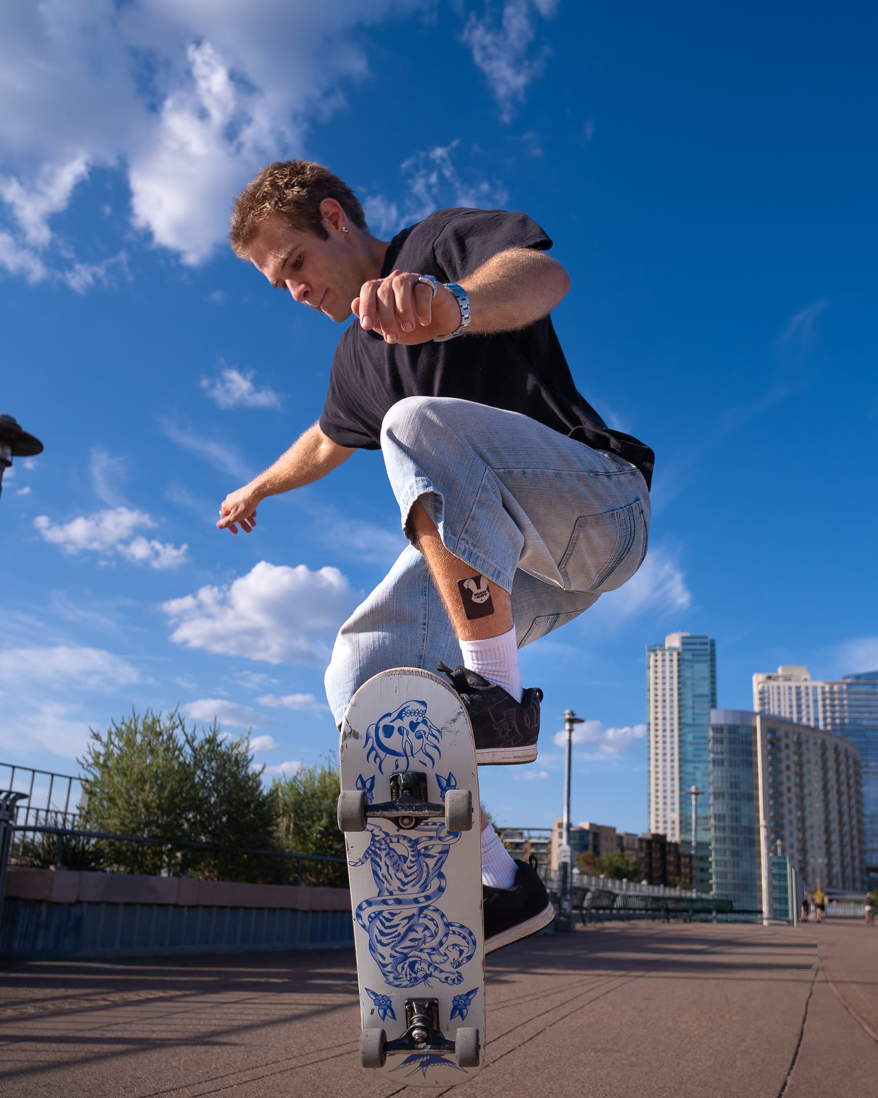 Skateboarder mid-kickflip in front of the Austin skyline, shot by BC Media