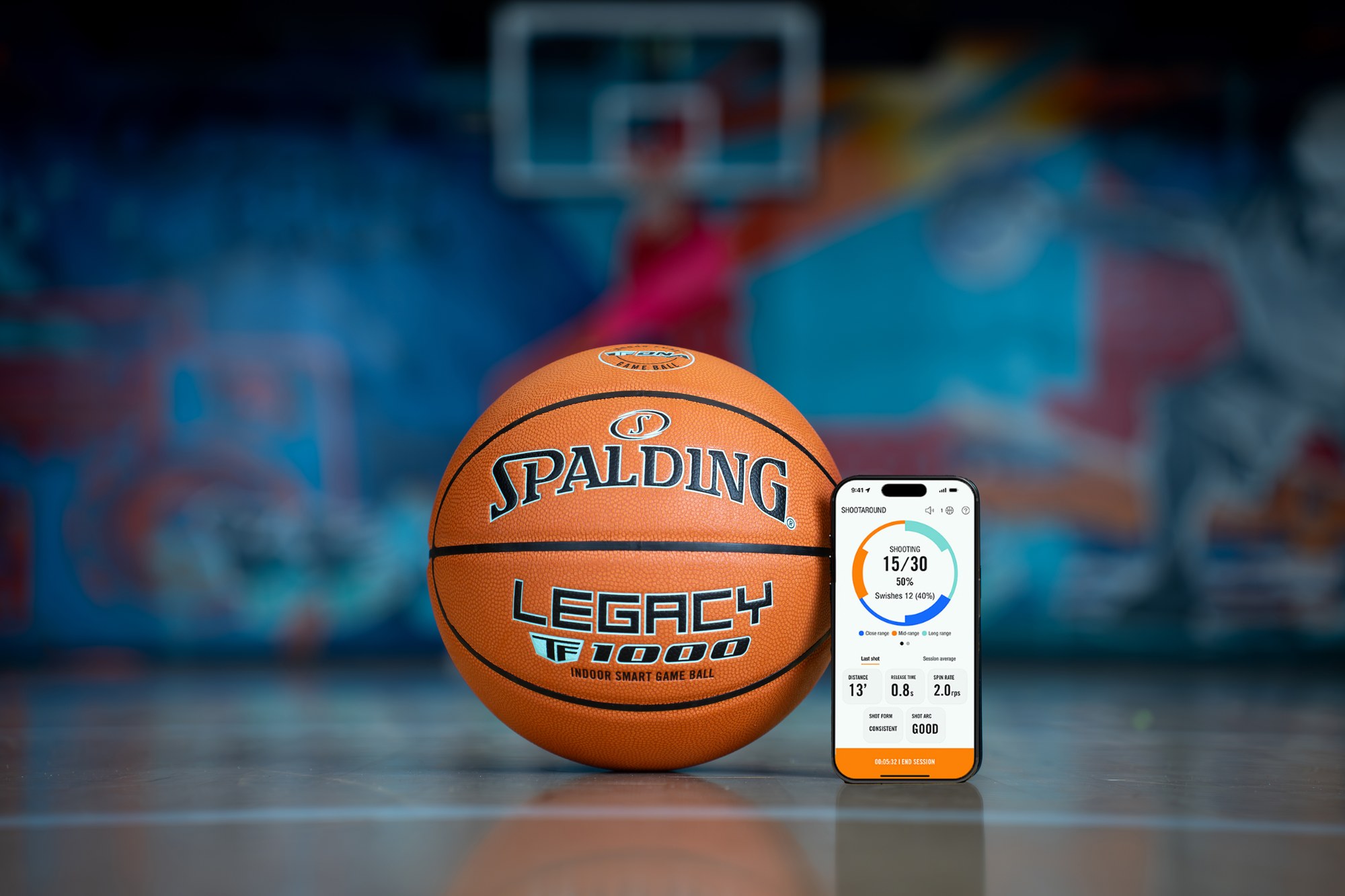 Spalding Legacy TF-1000 basketball beside a phone showing the shot-tracking app, court mural behind